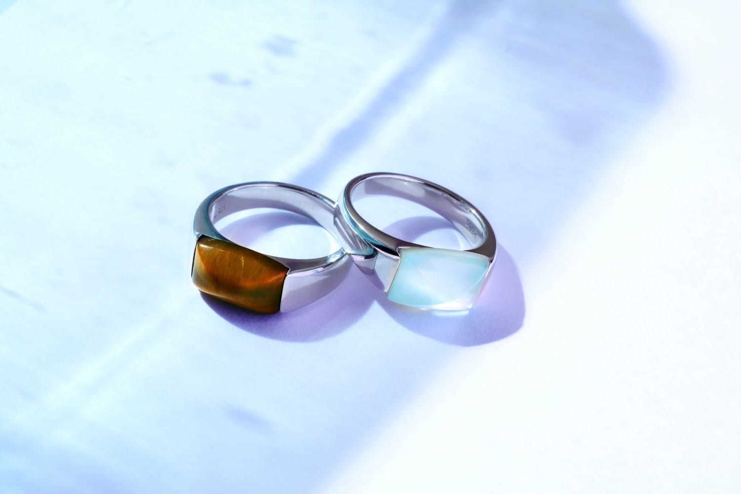 「MASS リング」右) ブルートパーズ、シェル 33,000円+税 、左) タイガーアイ 28,000円+税