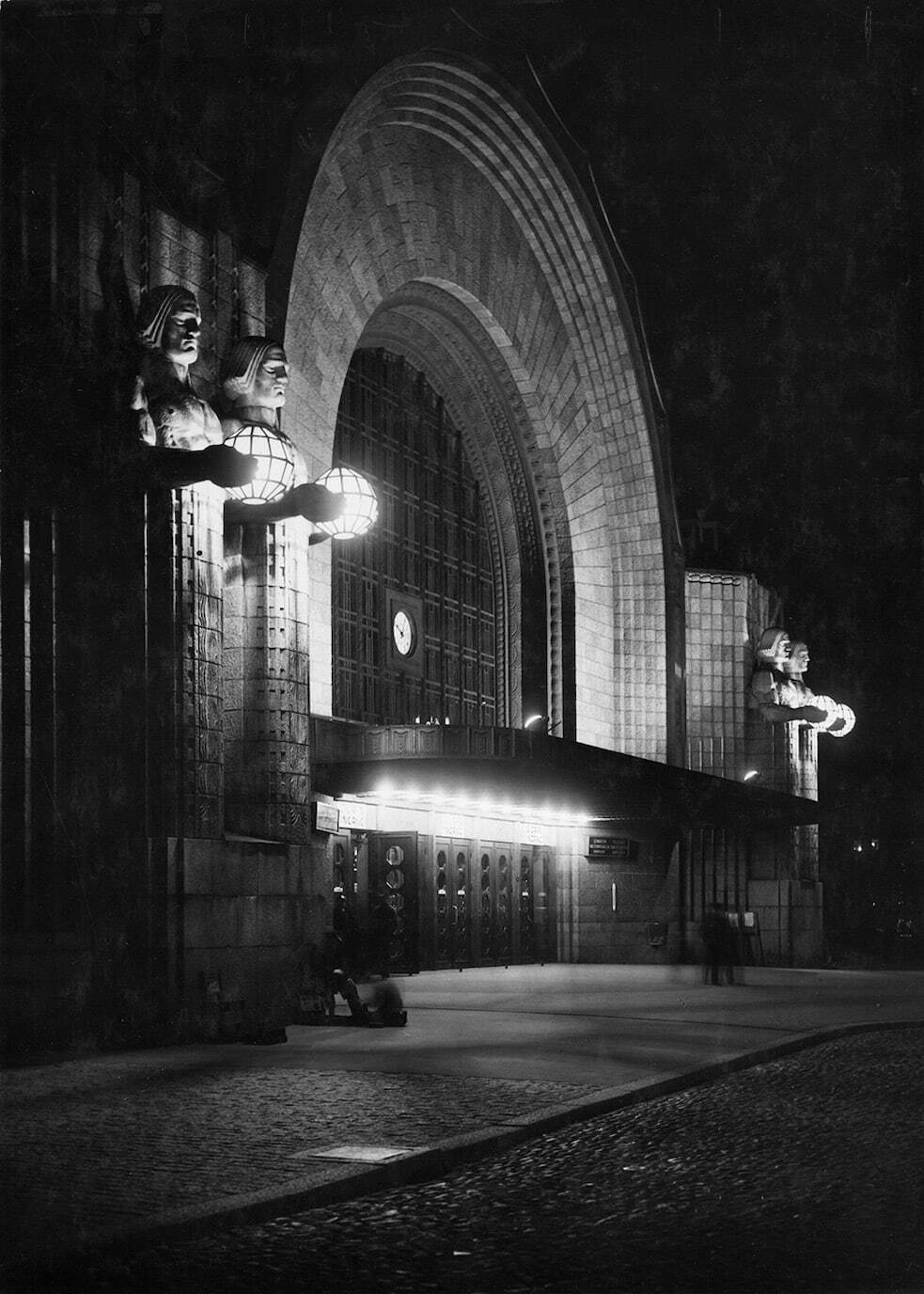 夜のヘルシンキ中央駅玄関、エーミル・ヴィークストロムによる彫像《ランタンを持つ人》 Photo ©Museum of Finnish Architecture/ Foto Roos