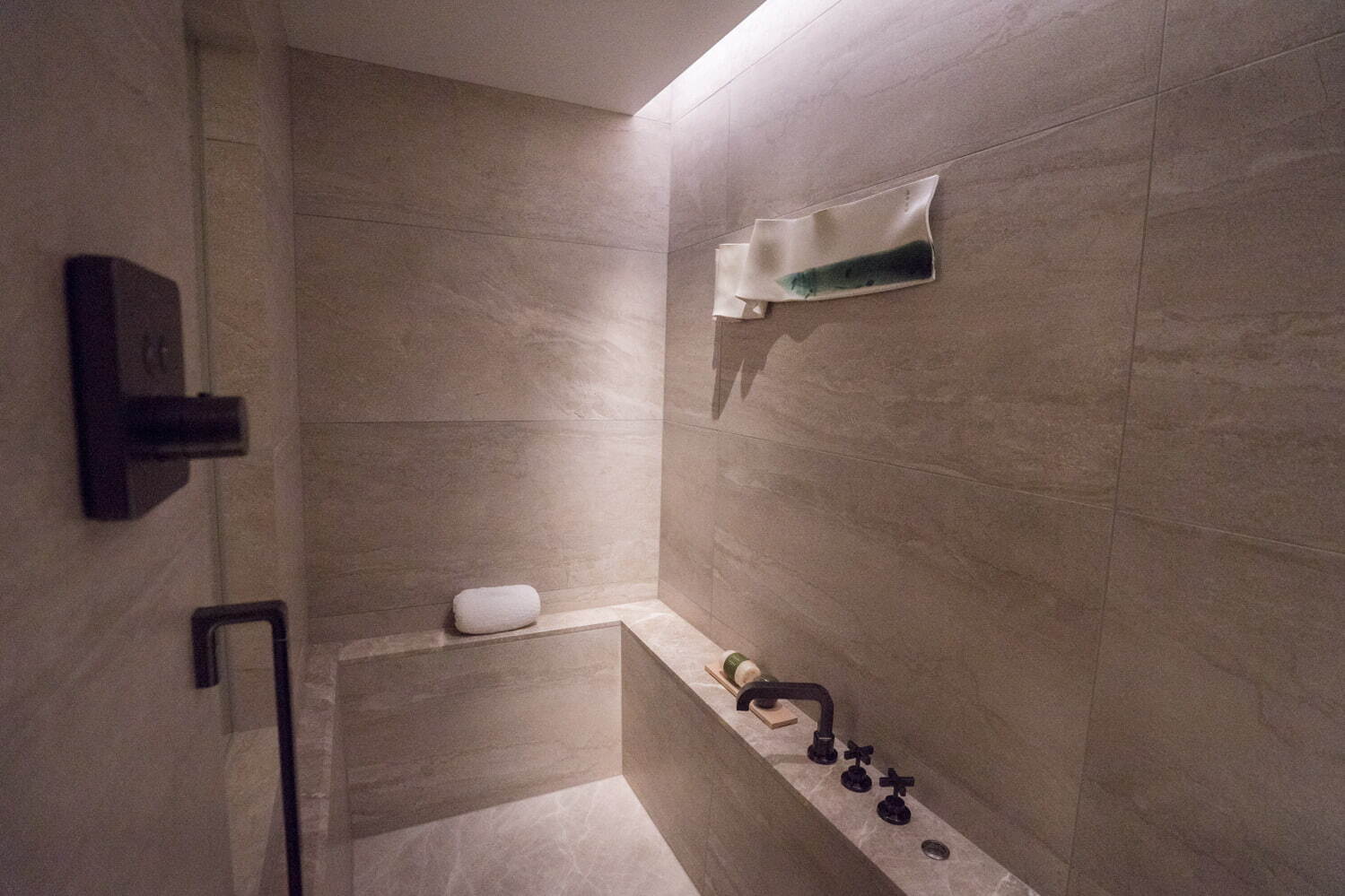 〈バスルーム〉バスタブは高級感溢れる石造り。シャワーはハンドシャワーとレインシャワーが揃う。日本人調香師がフレグランスを手掛けたバスアメニティは、京都の自然から着想を得た爽やかな香り。